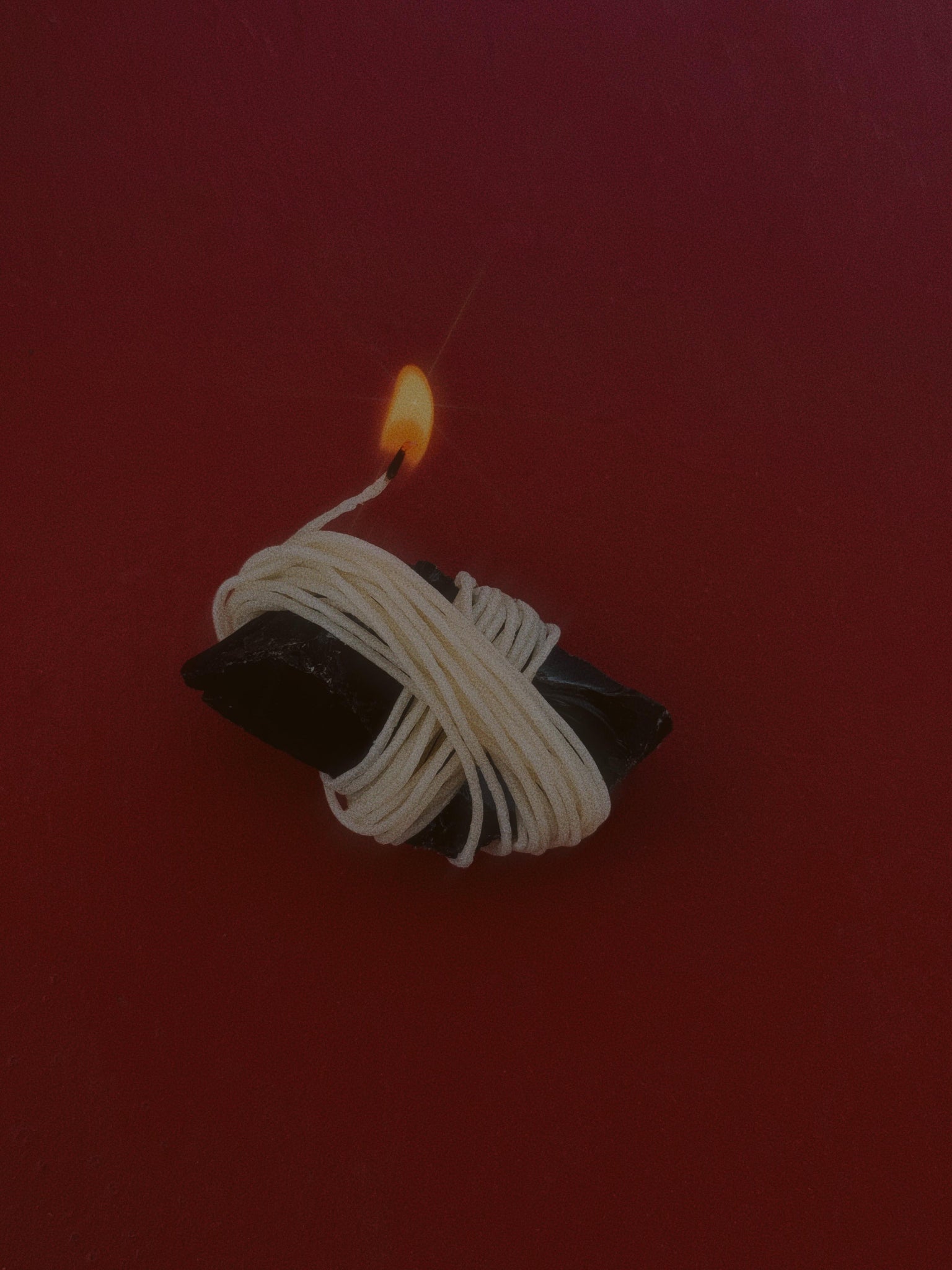 Lit hemp wick wrapped around Obsidian which is perfect for lighting your cannabis. This way you don't inhale butane from a lighter. This tool helps you to raise your ritual.