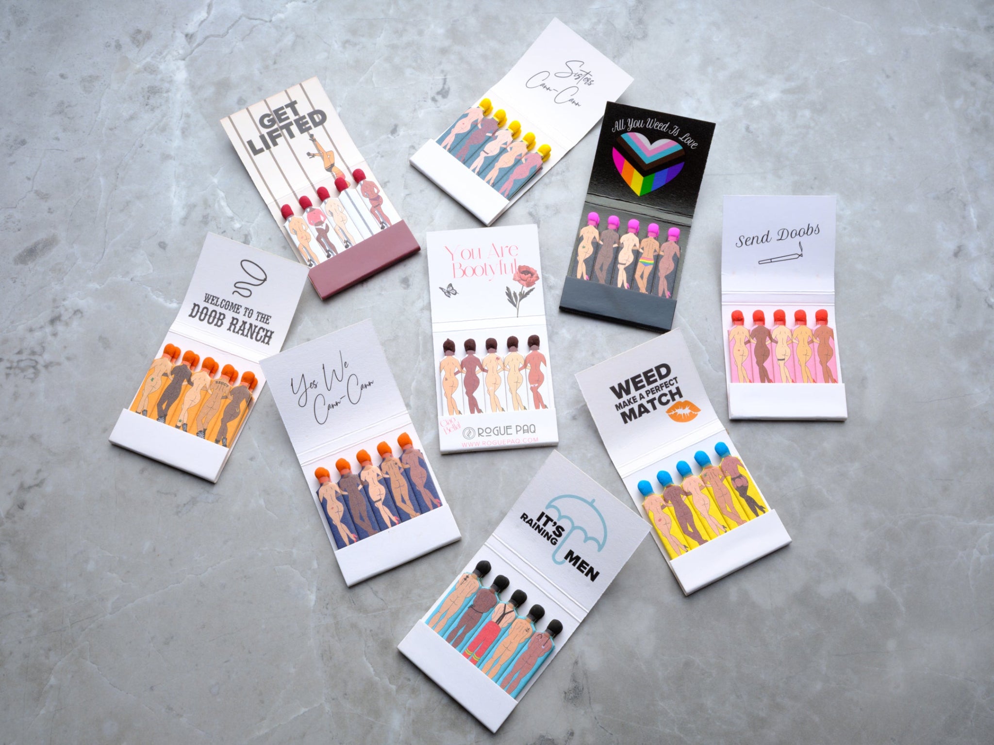 9 different styles of SendNudes vintage inspired matchbooks. The figures are male and female nude dancers in a can-can style. Each books celebrates body positivity and inclusivity.