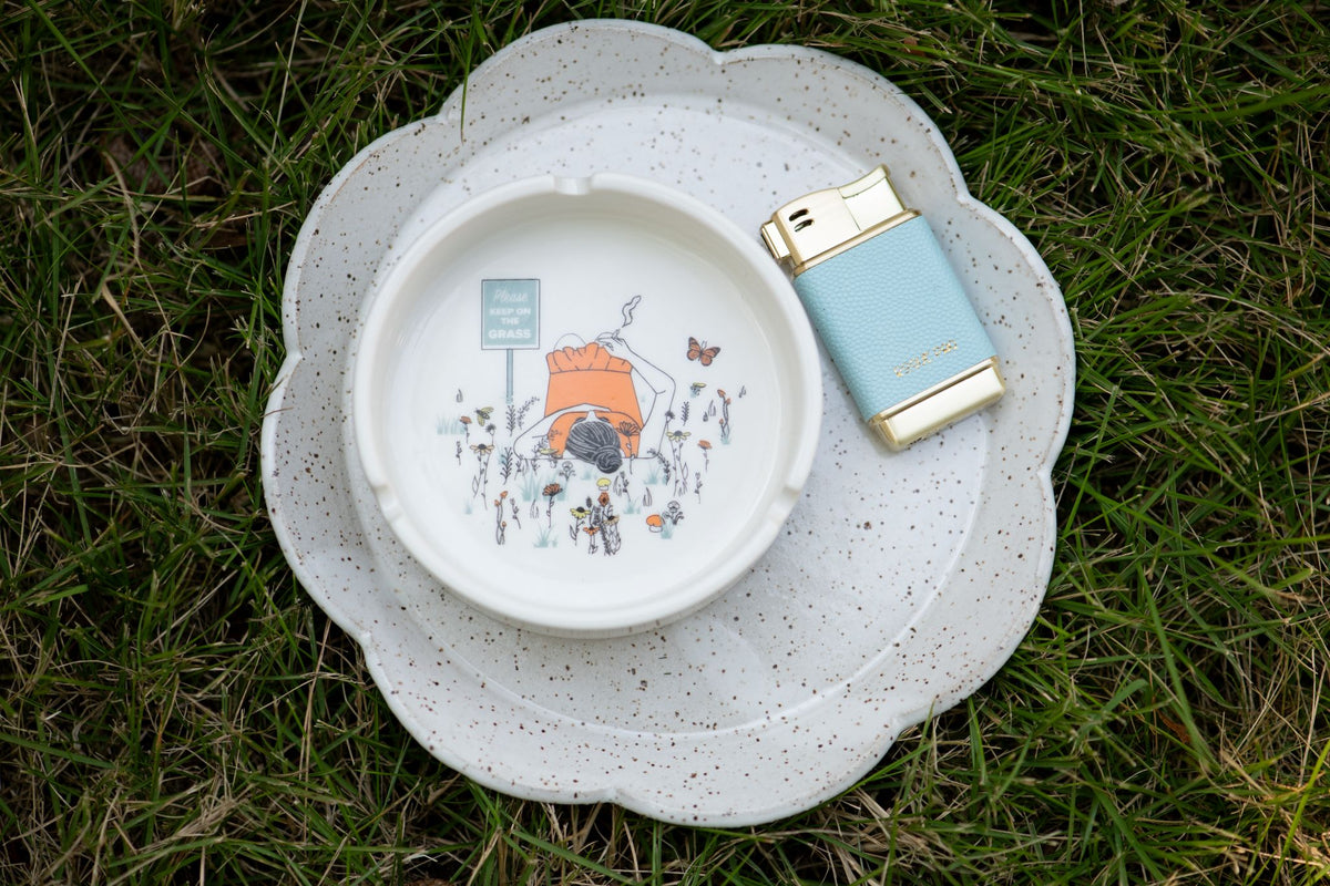 Please Keep On The Grass Ashtray with our sky blue butane lighter styled in the grass. 