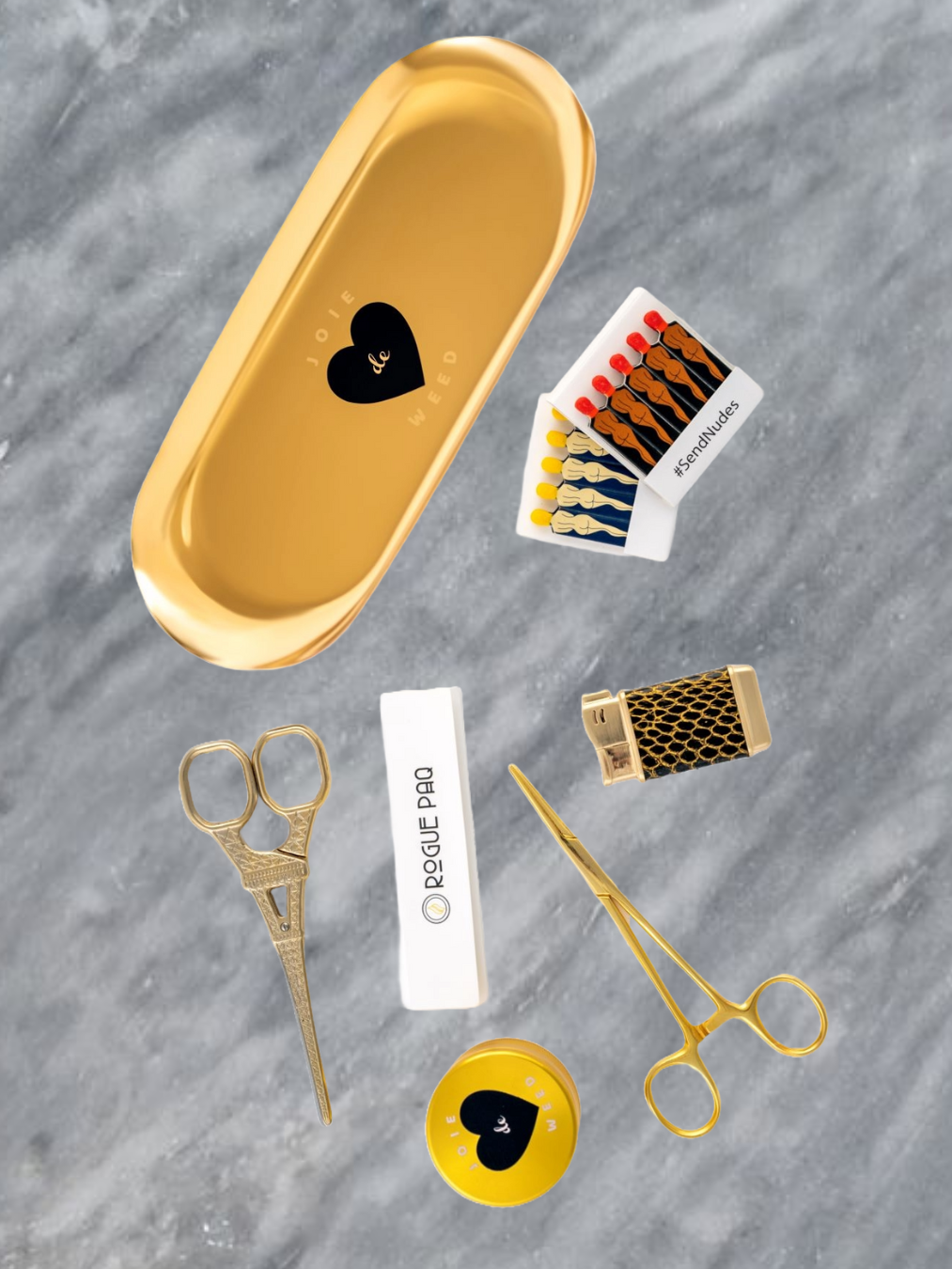 A luxury cannabis gift set featuring the gold 50mm 'Joie de Weed' 4-piece grinder, a booklet of Rogue Paq unbleached hemp rolling papers, Eiffel Tower Scissors, a refillable lighter, two books of SendNudes matches, and a pair of gold-toned hemostat jay clips. The set is presented in a minimalist, high-contrast arrangement that highlights the polished gold hardware.